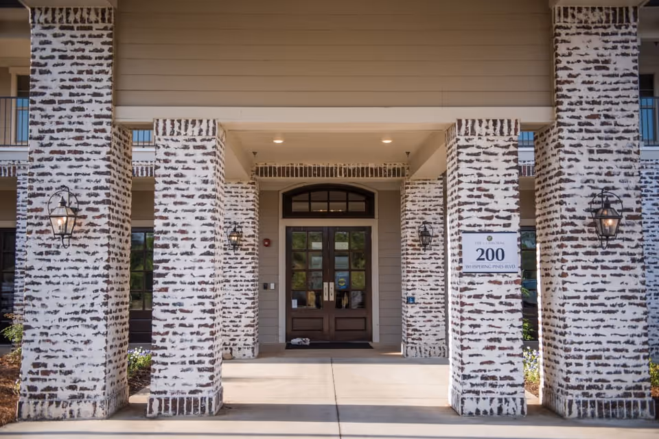 Covered entrance with whitewashed brick columns flanking double wooden doors and lanterns, with a sign reading "200".