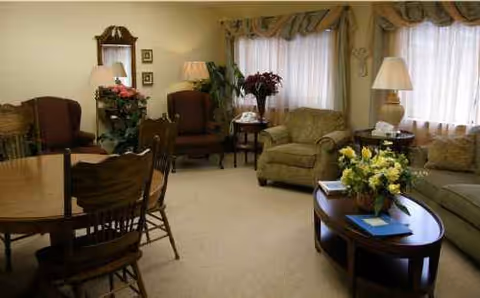 Cozy communal living room with sofas, chairs, coffee tables, and floral decor.