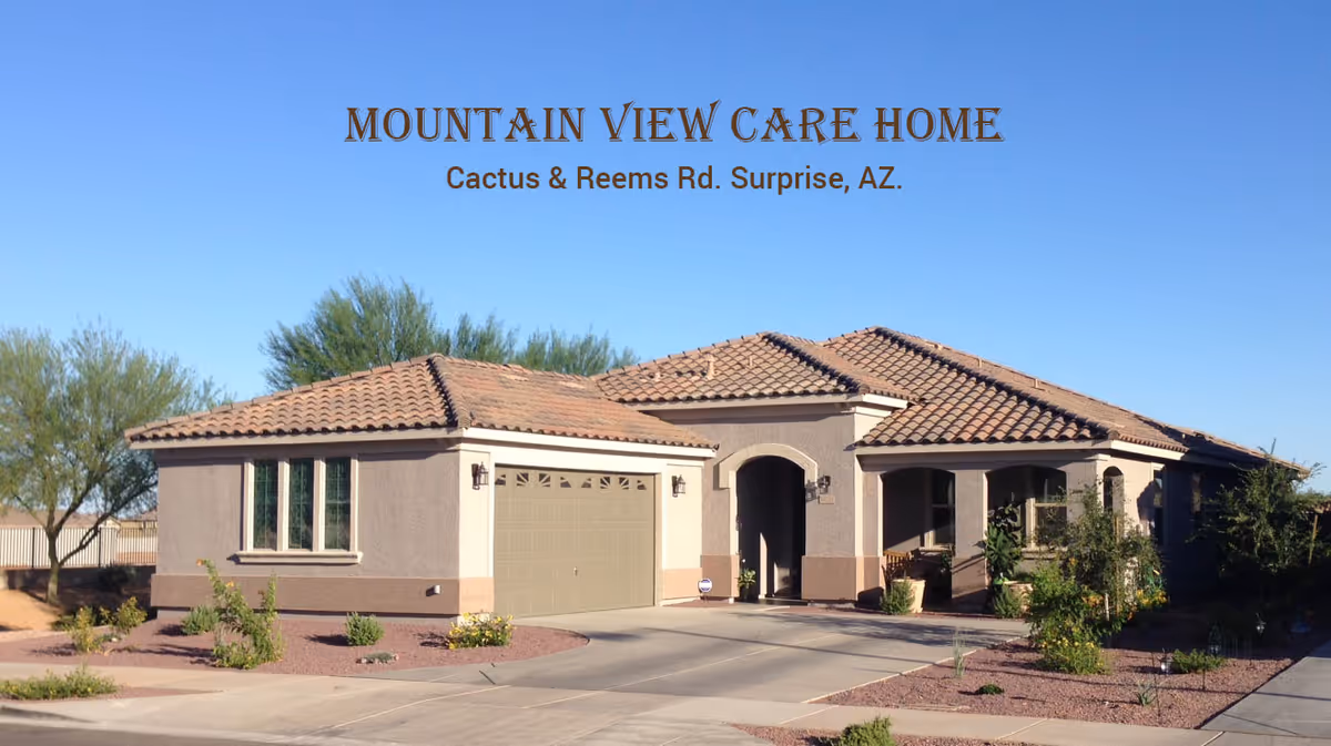 Front exterior of a single-story beige stucco care home with a tiled roof, attached garage, and desert landscaping under a clear blue sky with the text 'MOUNTAIN VIEW CARE HOME' overlaid at the top.