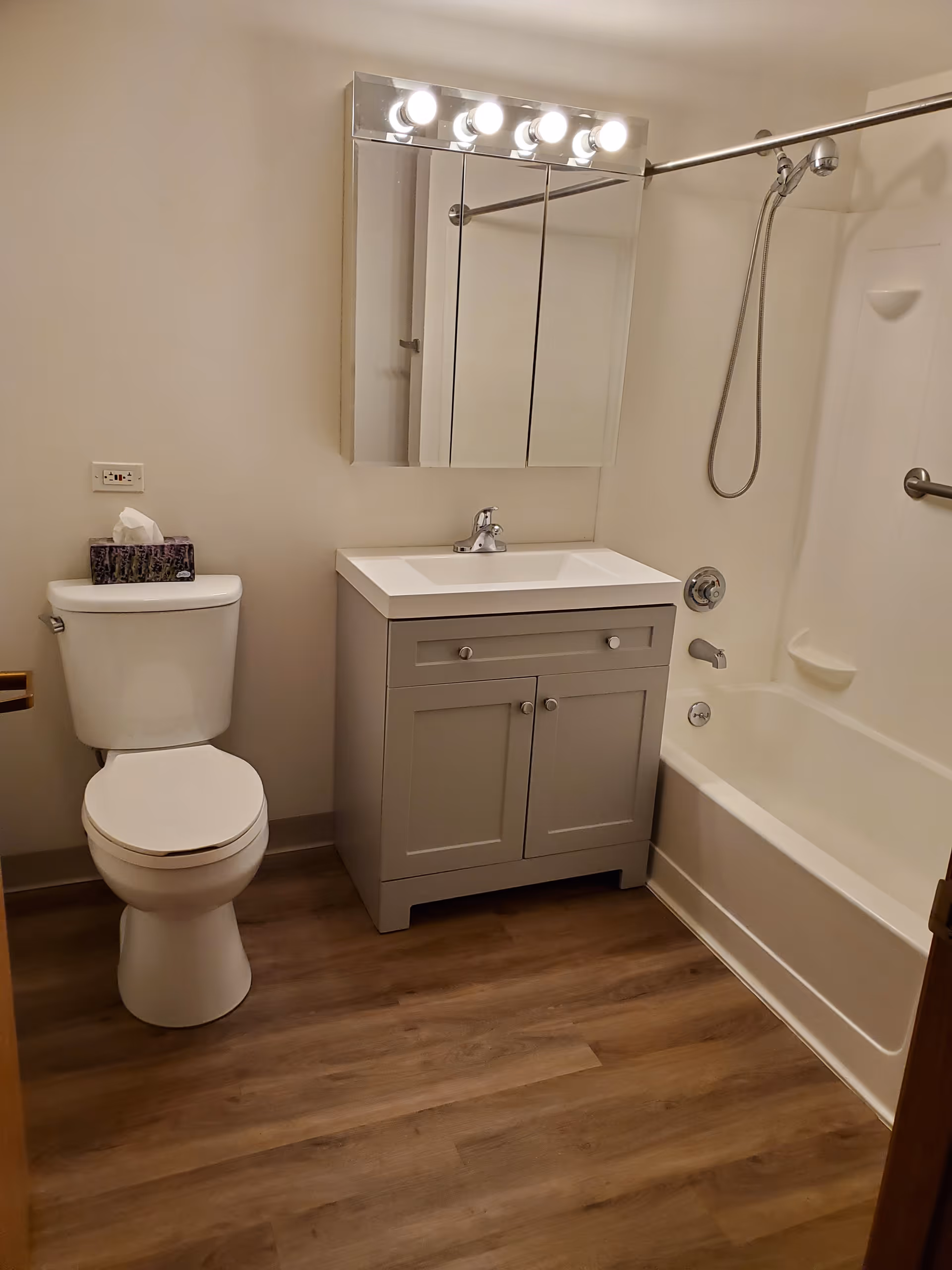 Small modern bathroom with a toilet, sink vanity and mirrored medicine cabinet next to a bathtub and shower.