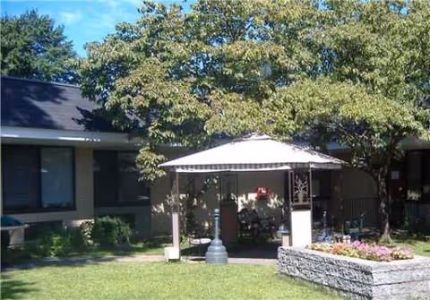 Exterior view of Bloomfield Health Care Center with a shaded patio and garden.