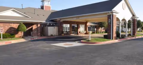 Brick senior living facility with a covered entrance and spacious parking area.