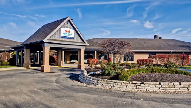 Exterior view of a senior living facility entrance with a landscaped circular garden.