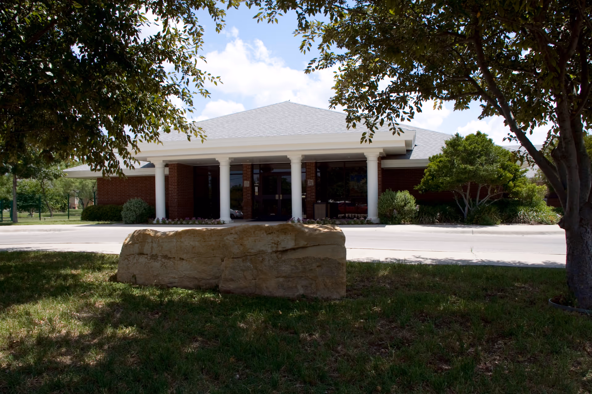 The exterior view of Sagecrest Care Center featuring a brick facade and columns, surrounded by greenery.