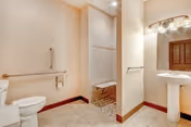 Accessible bathroom with a toilet, pedestal sink, and a walk-in shower featuring a built-in bench and grab bar.