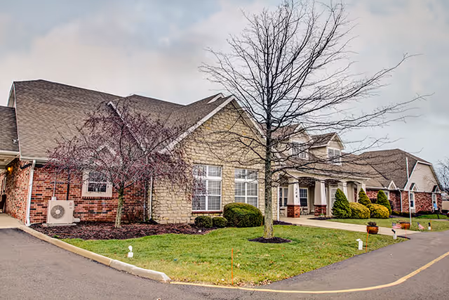 Exterior view of a senior living facility with brick facade and landscaped front yard.