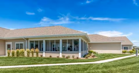 Single-story senior living facility with a glass-enclosed front porch and manicured lawn.