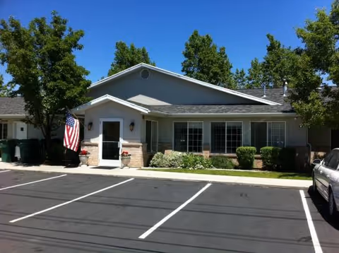 Stonewood Villa front exterior with parking lot, shrubs, and an American flag by the entrance.
