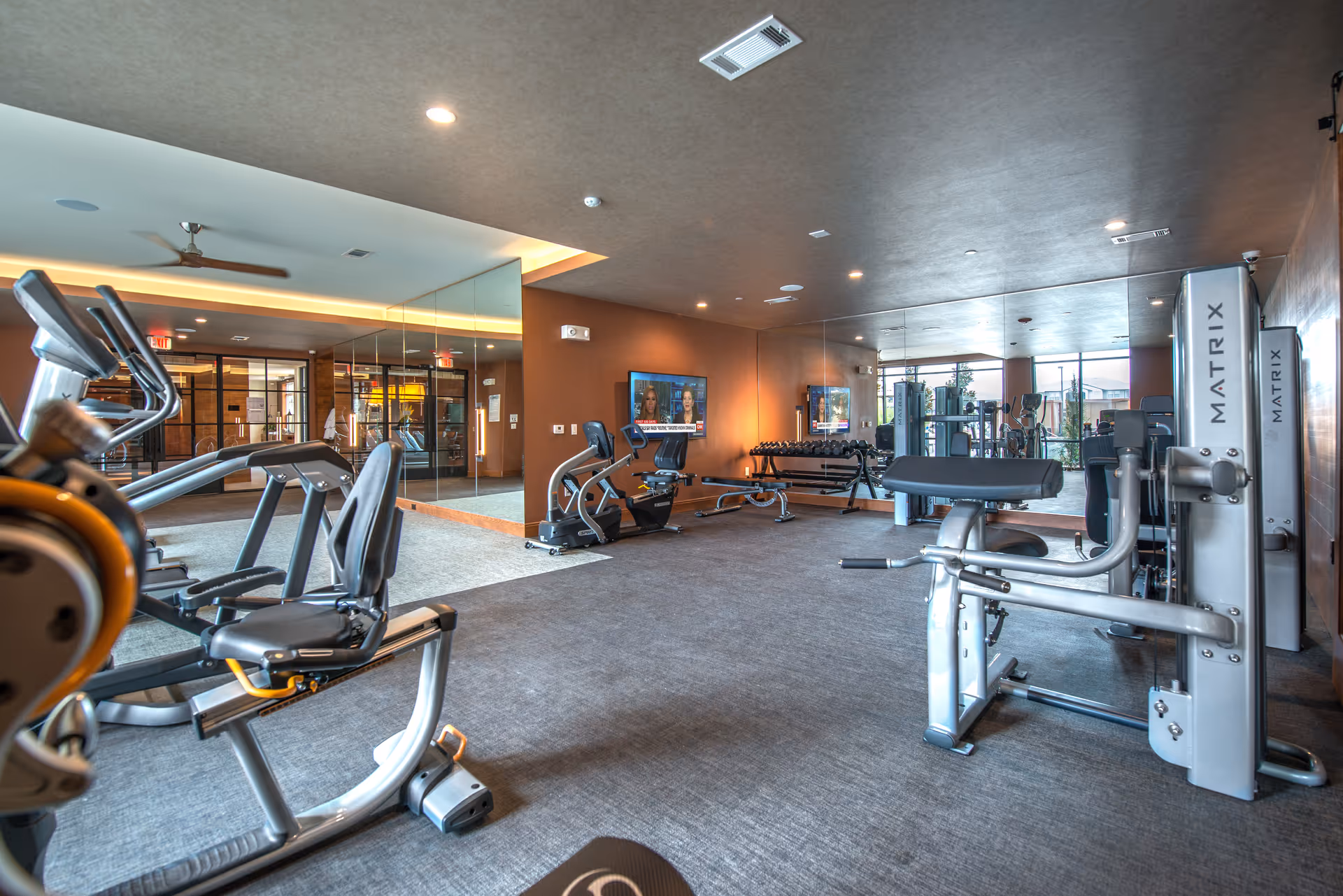Well-equipped fitness center with cardio machines, weight equipment, mirrors and TVs.