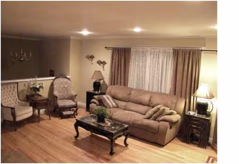 Cozy living room with sofa, armchairs, coffee table, lamps, and curtains.