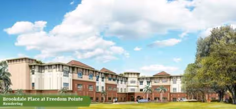 Exterior view of a multi-wing senior living building with a manicured lawn.