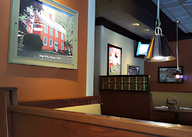 Interior dining area with wooden booths, pendant lights, and framed artwork on warm-colored walls.