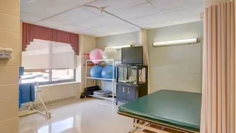 Therapy room with exercise balls, equipment, and a padded treatment table.