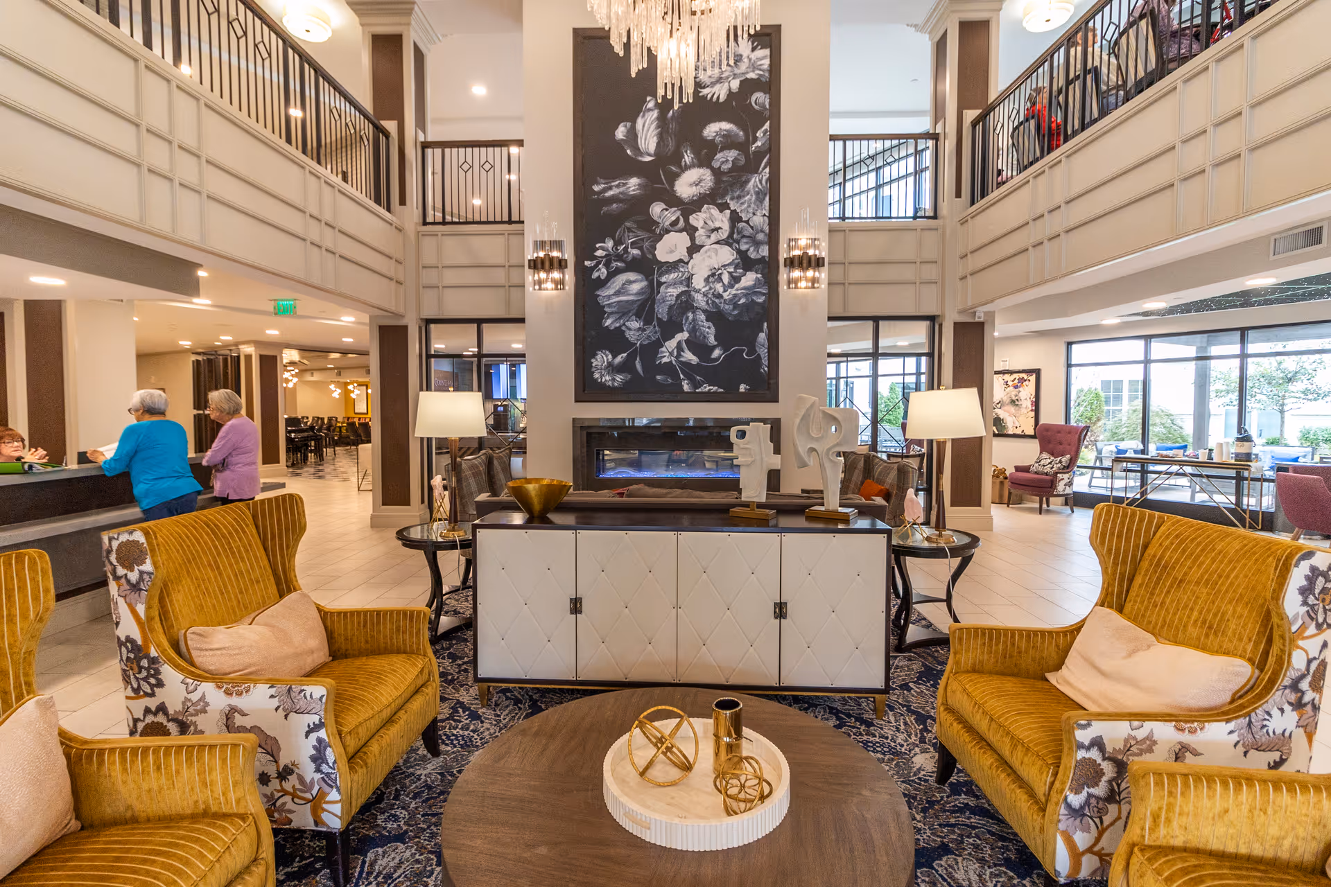 Spacious two-story lobby lounge with seating, chandelier, fireplace, and reception desk.