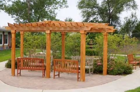 Wooden pergola with benches in a sunny outdoor Riverside courtyard.