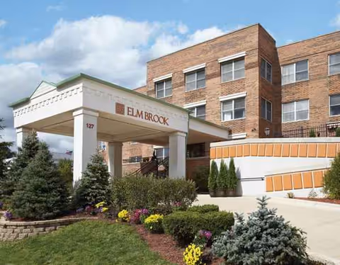 Exterior view of Grove of Elmhurst entrance with brick building and landscaped front garden