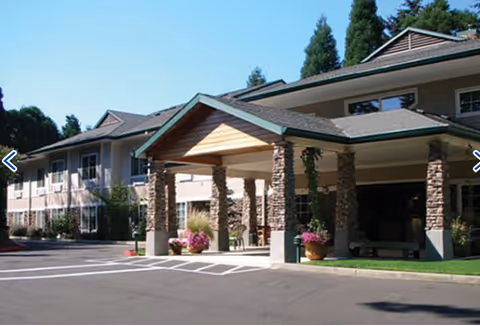 Exterior view of Woodland Heights Assisted Living entrance with covered drop-off and landscaping.