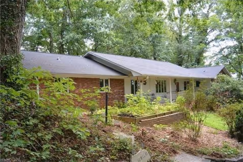 Exterior view of Sunflowers Homes: a single-story brick building surrounded by trees.
