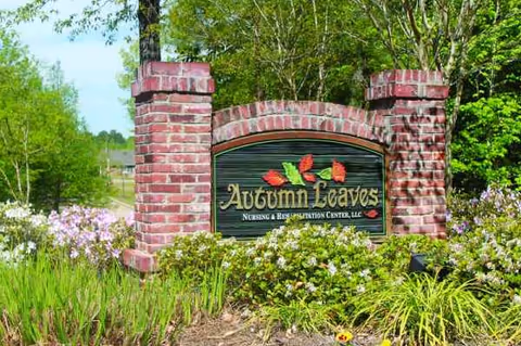 Brick entrance sign for Autumn Leaves Nursing & Rehabilitation Center, LLC, amid landscaped greenery.