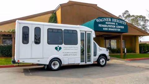 White shuttle bus parked in front of Wagner Heights Nursing and Rehabilitation Center exterior.
