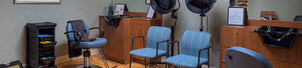Small salon area with styling chairs, hooded hair dryers, wash basins and cabinetry.