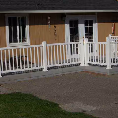 Front entrance of a senior living home with white railing and brown siding.