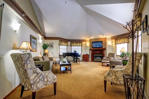 Cozy senior living lounge with sofas, chairs, fireplace, and a piano.