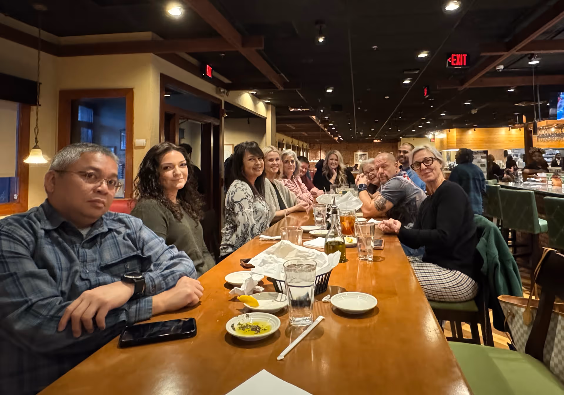 A large group of people seated at a long restaurant table indoors, facing the camera.