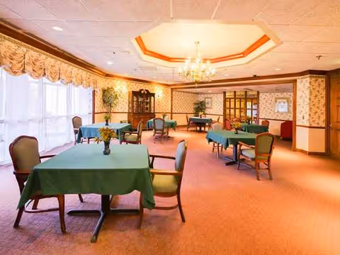 Empty senior dining room with green tablecloths and a chandelier.