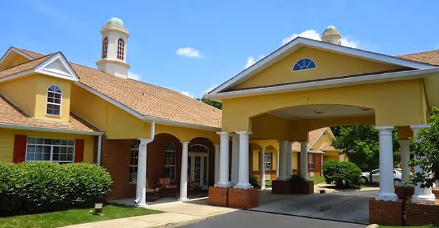 Exterior view of Belvedere Commons of Franklin showing a yellow building with white columns, a covered entrance, and a clear blue sky with a few clouds.