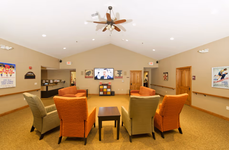 Cozy lounge with orange and green chairs surrounding a small central table.