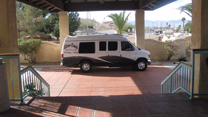White van labeled Silver Creek Assisted Living parked under a covered entrance at the facility.