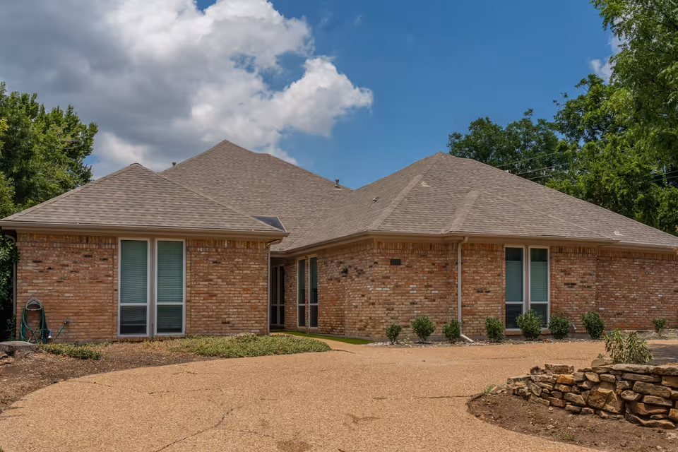 A brick, single-story senior living facility with a front entrance and landscaped walkway.