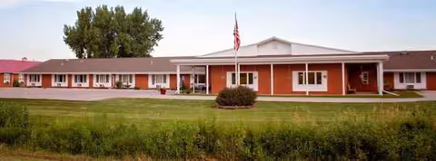 Goldenrod Manor exterior: a single-story brick building with a flagpole and manicured lawn.
