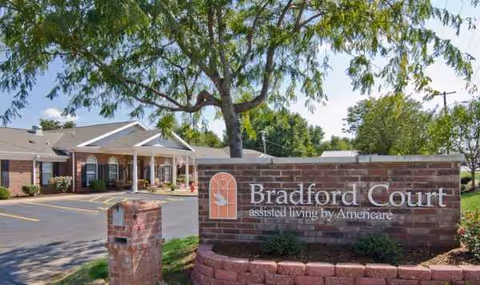 Exterior view of Bradford Court assisted living entrance with brick sign and trees