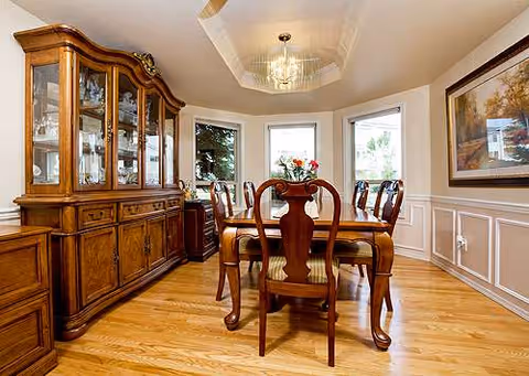 Elegant dining room with wooden table, chairs, china cabinet, and a chandelier.