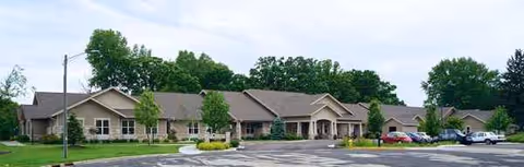 Exterior view of At Home Again Memory Care Rio facility, a single-story building with parking.