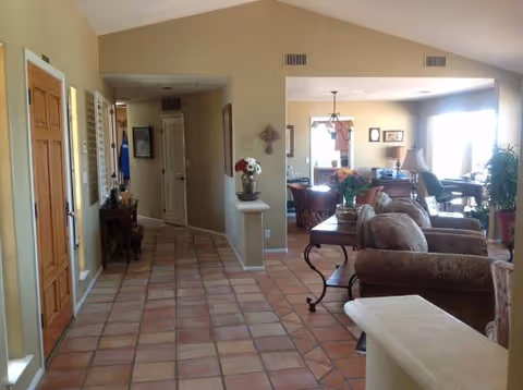 Hallway opens into a spacious living area with sofas, tables, and potted plants.