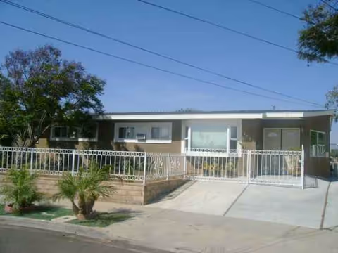 Front exterior view of Canyon Guest Home with a gated entrance and shrubs.