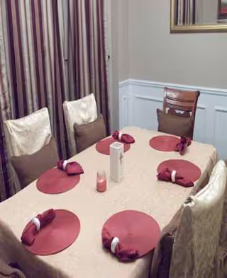A dining room table set with pink placemats and napkins in a senior living facility.