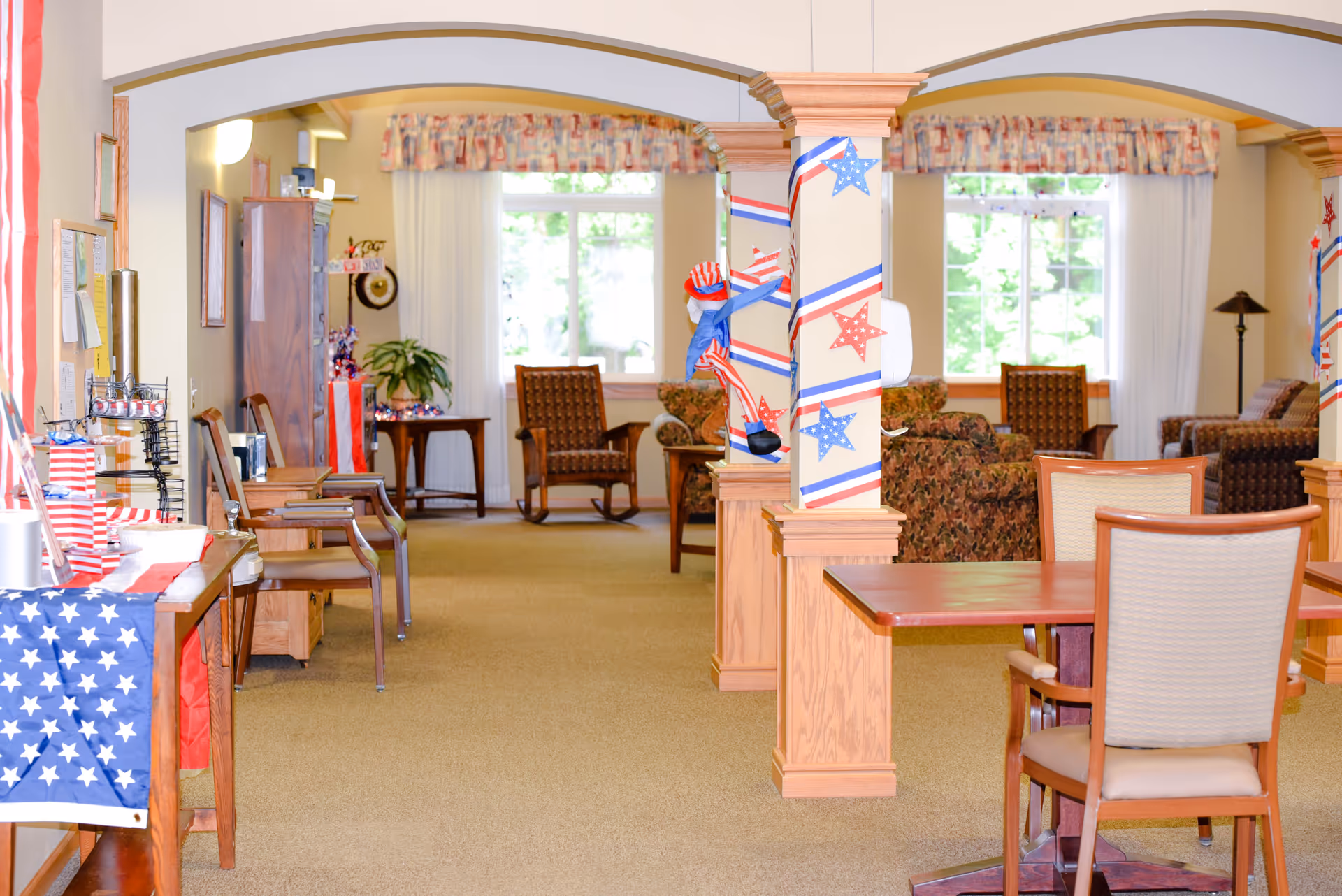 Bright communal seating area in a senior living facility decorated with patriotic red, white, and blue accents.