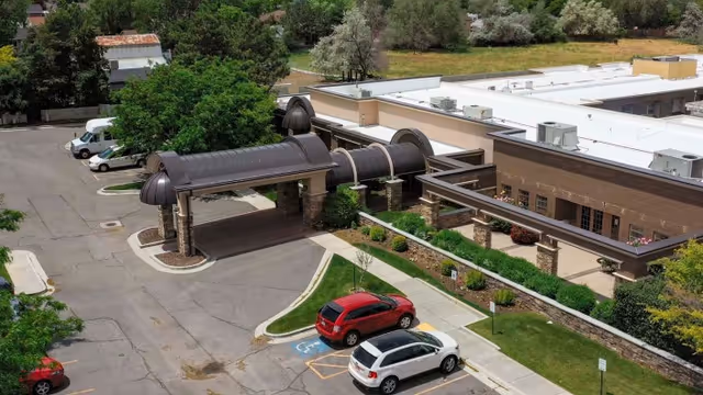 Aerial view of the entrance to Copper Ridge Health Care facility showing a covered drop-off area with stone pillars, adjacent parking spaces including a handicapped spot, and surrounding greenery.