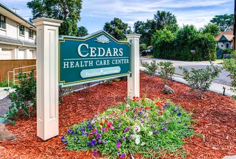 Cedars Health Care Center sign with landscaped flower bed and trees outside the building.
