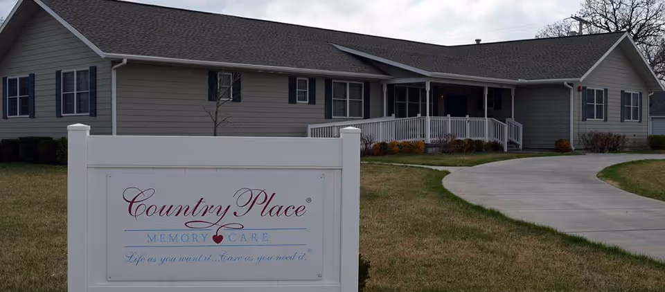 Front view of a Country Place Memory Care facility with a curved driveway and sign
