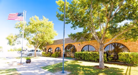Focused Care at Odessa brick senior living facility with arched windows, flagpole, trees, and manicured landscaping.