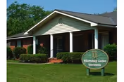 Front view of a single-story senior living facility with a covered entrance and landscaped lawn.