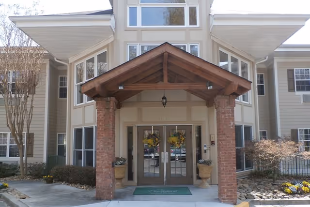 Exterior view of Legacy Ridge at Buckhead entrance with brick pillars and glass doors.