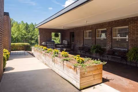 Brick exterior patio with raised flower planters, benches, and seating along the building.