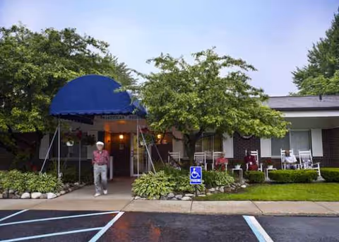 Entrance to American House Westland Venoy Senior Living with a blue canopy and residents outside.