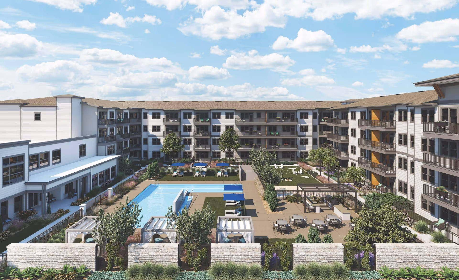 Outdoor courtyard area of a senior living facility with a swimming pool, lounge chairs with blue umbrellas, cabanas, tables and chairs, green lawn with trees, and a multi-story building surrounding the courtyard under a partly cloudy sky.